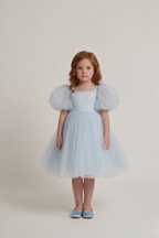 Front view of sky blue puff sleeve tulle flower girl dress worn by a young girl